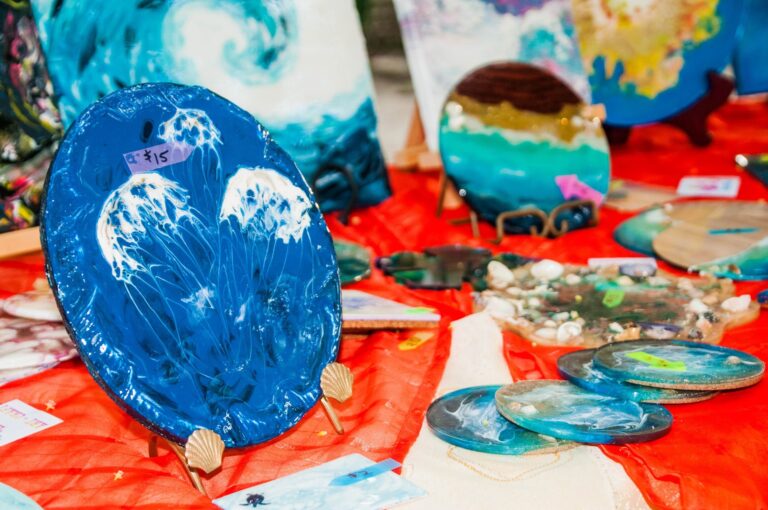 Colorful handmade glass art pieces displayed on a table at a market in Roatan, Bay Islands, Honduras, showcasing vibrant blues, greens, and natural sea-inspired designs.