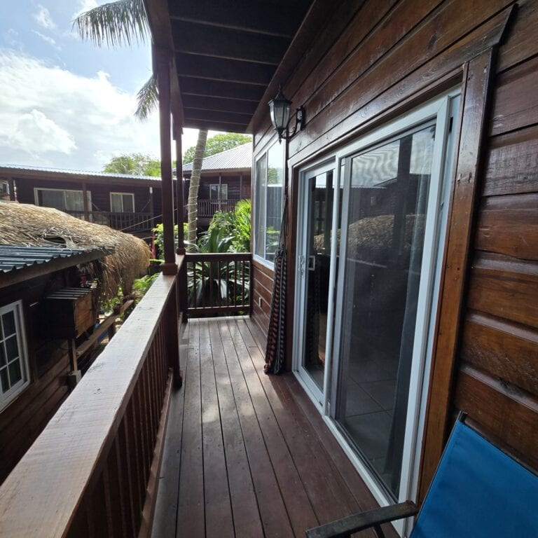 Wooden balcony with sliding glass doors overlooking lush tropical greenery on Roatan in the Bay Islands of Honduras.