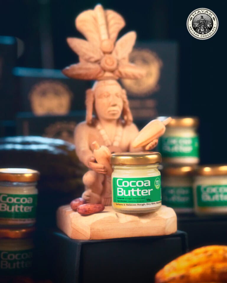Handcrafted indigenous figure holding a cocoa pod with jars of cocoa butter in the background on Roatan, Honduras.