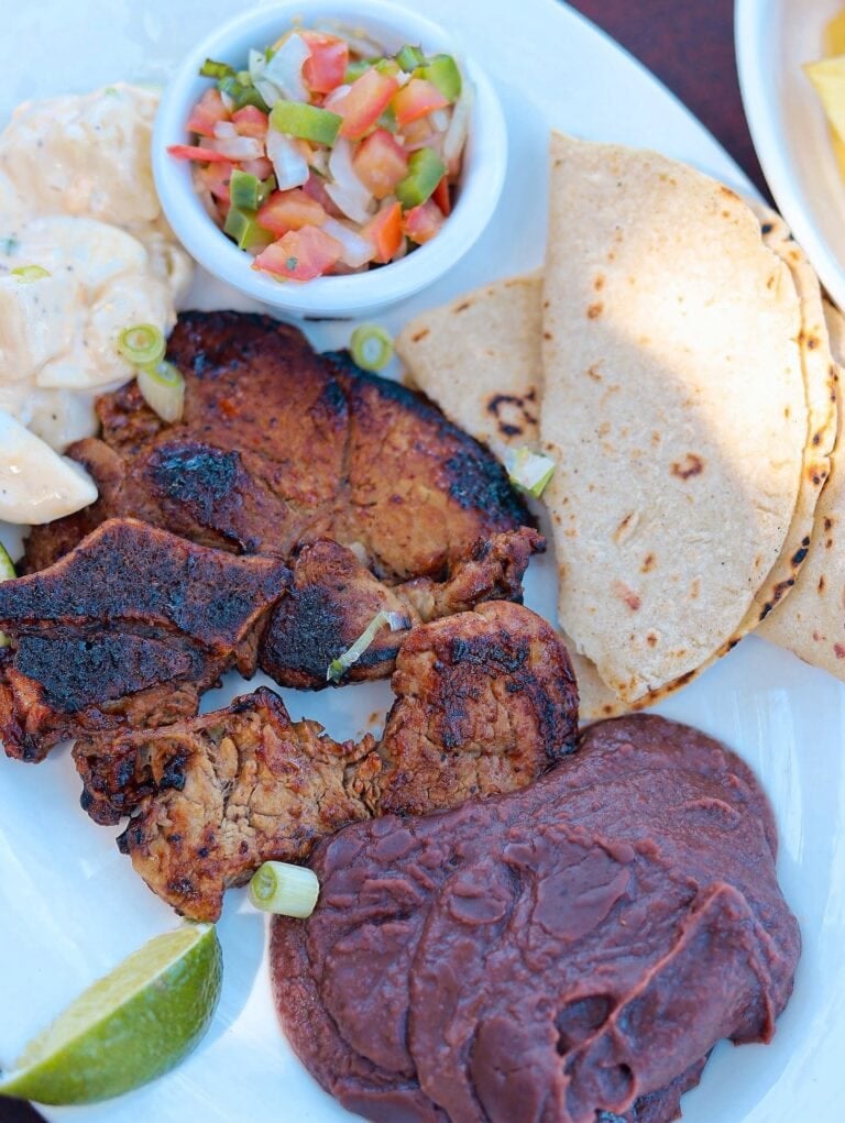 Close-up of a traditional Honduran plate with grilled meat, tortillas, and a fresh vegetable salad in Roatan, Honduras.