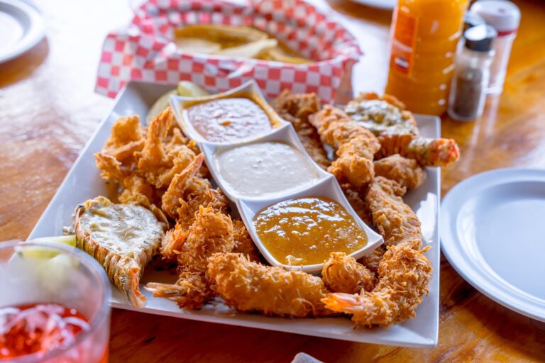 Fried shrimp with three dipping sauces on a white plate at Mutton Pepper Caribbean Grill.