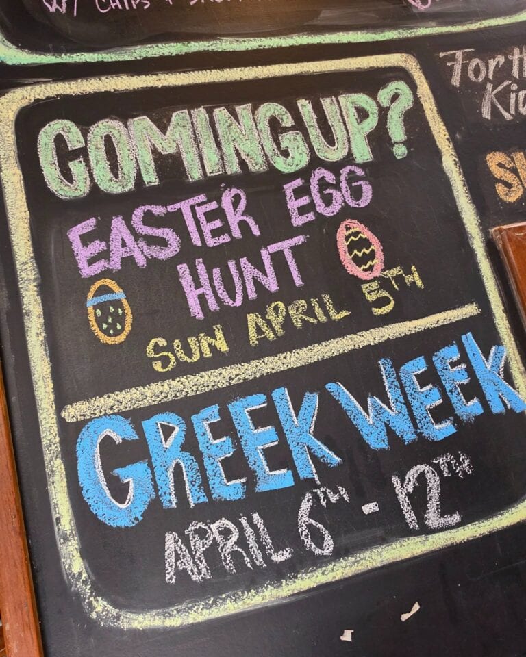 Colorful chalkboard sign advertising Easter egg hunt event.