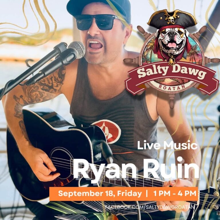 Ryan Ruun performing live music on a stage in Roatan, Honduras, with a guitar and wearing a tank top, sunglasses, and a cap, during a sunny outdoor event.