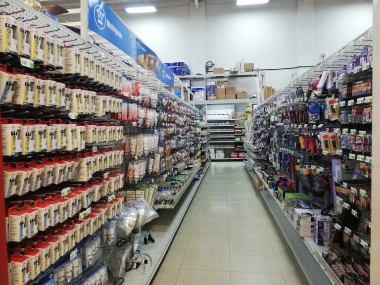 A hardware store aisle in Roatan, Honduras, displaying shelves stocked with various lighting bulbs, electrical supplies, and tools.