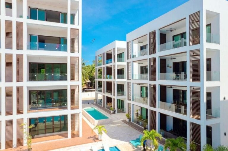 Modern white apartment buildings with glass balconies surrounding a swimming pool in Roatan, Bay Islands, Honduras.