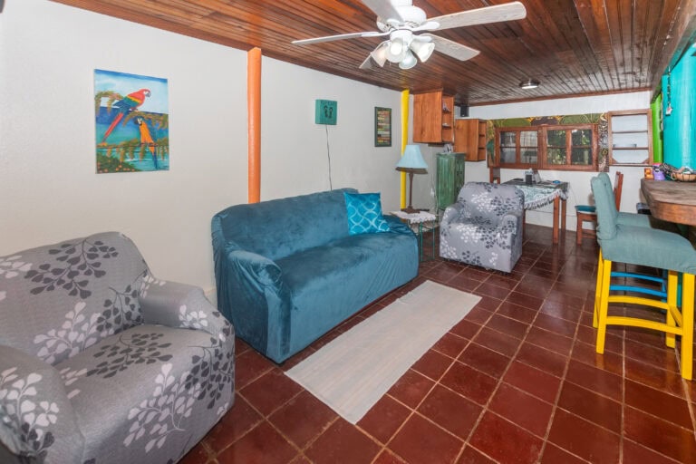 Living room in a colorful Roatan-themed home with vibrant wall art and wooden ceiling.