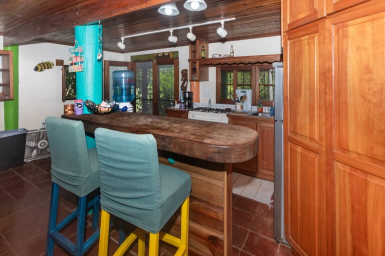 Interior view of a wooden kitchen in Roatan, Honduras featuring a large rustic countertop, wooden cabinets, and tropical decor including a fish wall ornament.