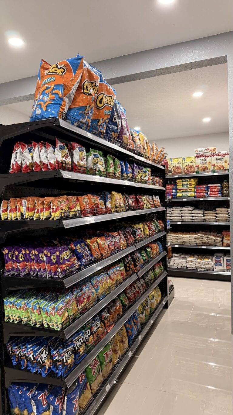 Shelves stocked with a variety of snack chips and packaged foods inside a grocery store on Roatan, Honduras.