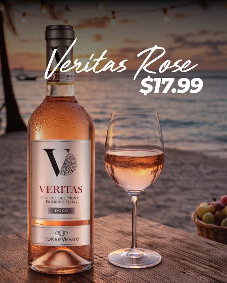 A bottle of Veritas rosé wine and a filled wine glass are placed on a wooden table at sunset, with a beach and ocean in the background on Roatan, Honduras.
