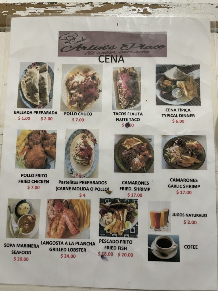 A menu from a restaurant in Roatan, Honduras, displays various dishes including seafood, fried chicken, grilled lobster, and drinks, with prices listed in US dollars.