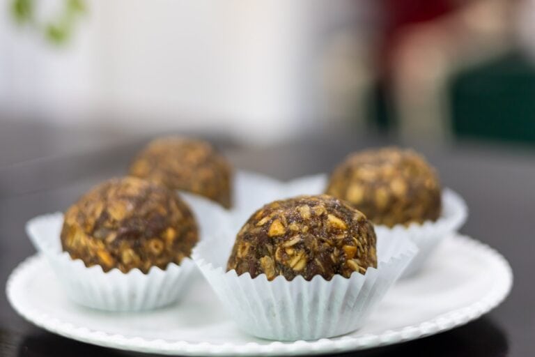 Close-up of homemade energy bites with nuts and chocolate on a white paper lace cupcake liner, set against a blurred background on Roatan, Honduras.