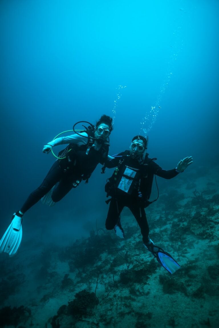 Two scuba divers swimming underwater in Roatan, Honduras.