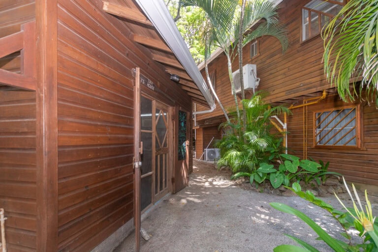 Wooden buildings with tropical plants and an air conditioning unit on Roatan, Bay Islands, Honduras, showcasing the rustic charm of local accommodations.