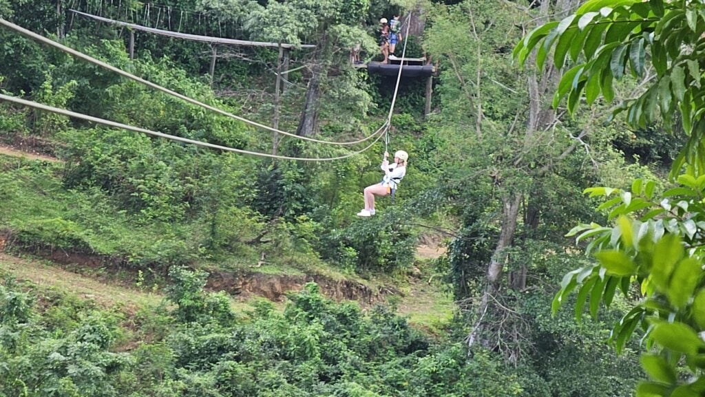 People ziplining through the lush green jungle canopy on Roatan in the Bay Islands of Honduras.