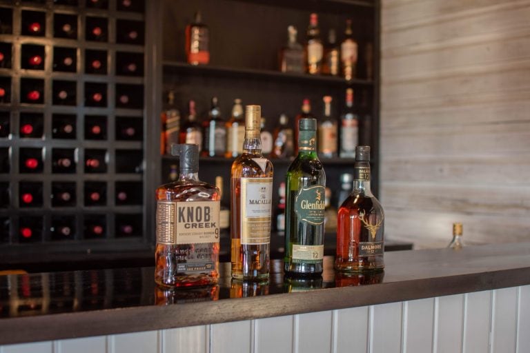 Bottles of whiskey and liquor are displayed on a bar counter inside a restaurant or bar in Roatan, Honduras.