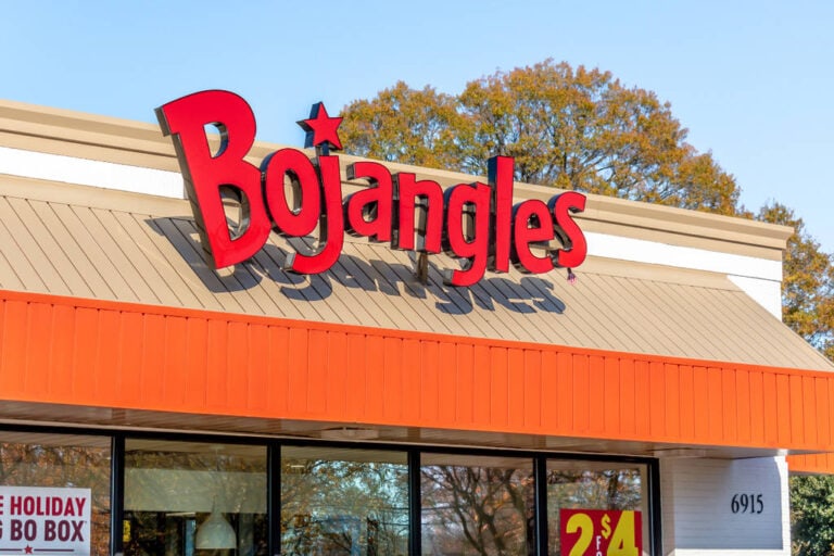 A Bojangles fast food restaurant with a prominent red logo and star sign, located in Roatan, Honduras, featuring an orange facade and large glass windows.
