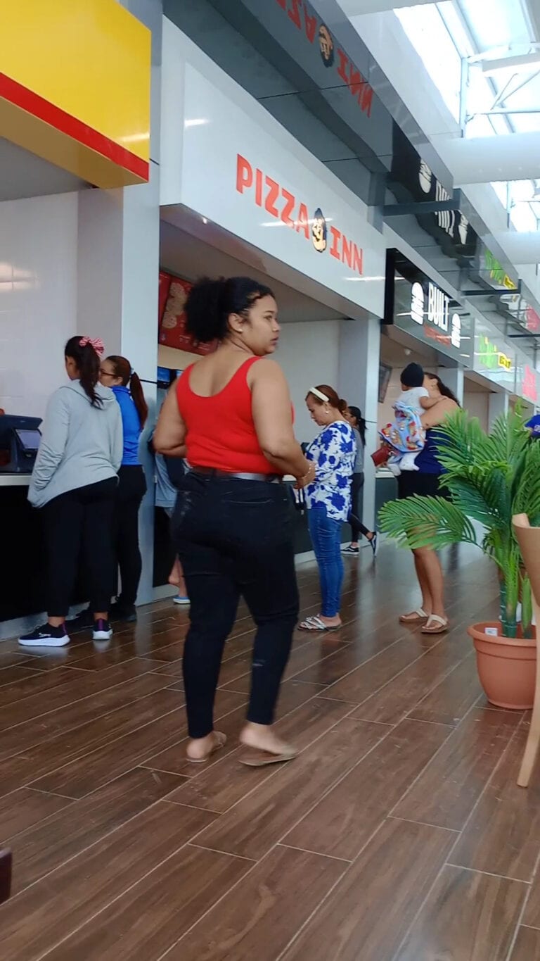 People wait in line at a Pizza Inn restaurant inside an airport or shopping mall in Roatan, Honduras.