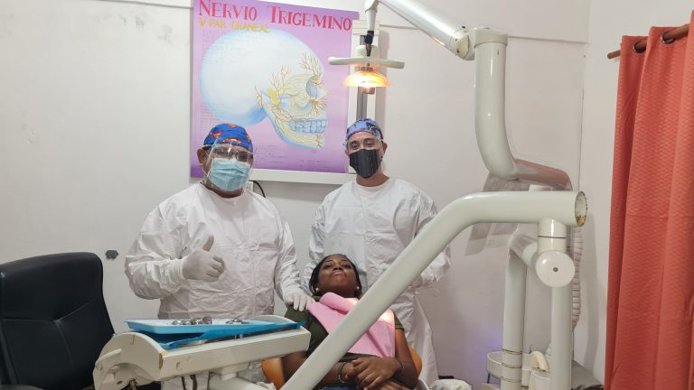 Dental professionals wearing masks and protective gear are seen attending to a patient in a dental clinic on Roatan, Bay Islands, Honduras.