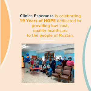 A group of healthcare workers in face masks and scrubs gathers inside a clinic on Roatan, Honduras, with colorful balloons and a decorated table celebrating 19 years of Hope.