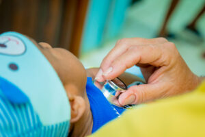 A person using a stethoscope examines a toddler’s chest during a medical check-up at a healthcare facility in Roatan, Honduras.