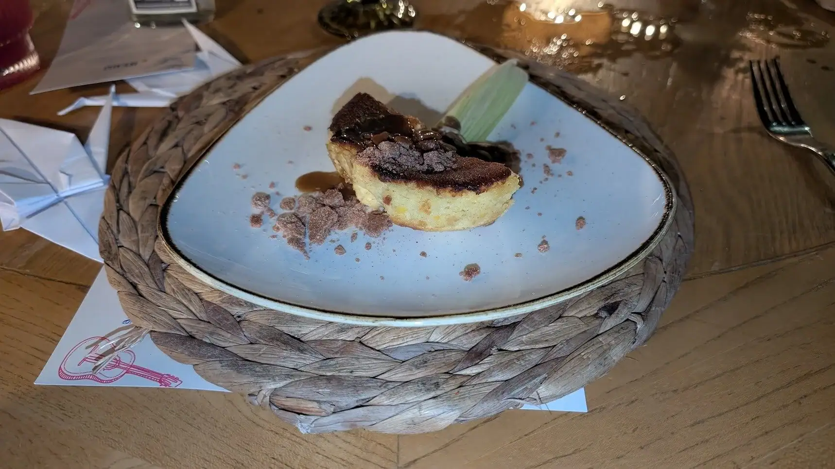 A slice of cheesecake with chocolate topping and cocoa powder on a decorative plate at a restaurant in Roatan, Honduras.