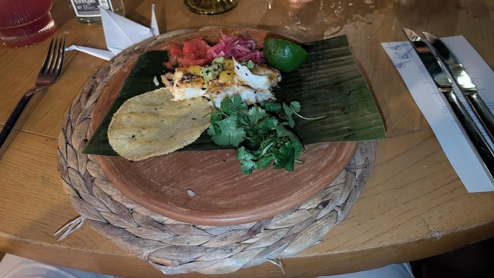 Delicious traditional Honduran seafood dish served on a wooden plate with fresh cilantro, lime, and plantain chips, displayed on a wooden table in Roatan, Honduras.