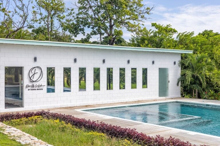 Modern white building with multiple narrow windows and a swimming pool in front.