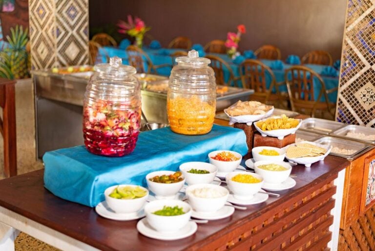 A colorful breakfast buffet setup with various tropical fruits, sauces, and condiments on Roatan, Honduras, offering a vibrant and inviting display for guests.