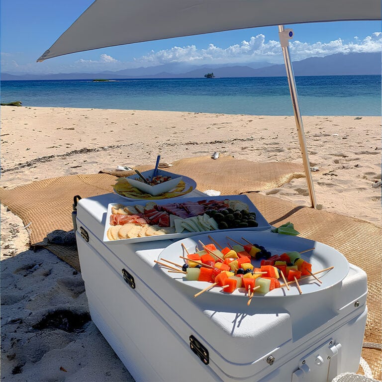 Beachside fruit and snack platter under an umbrella in Roatan.
