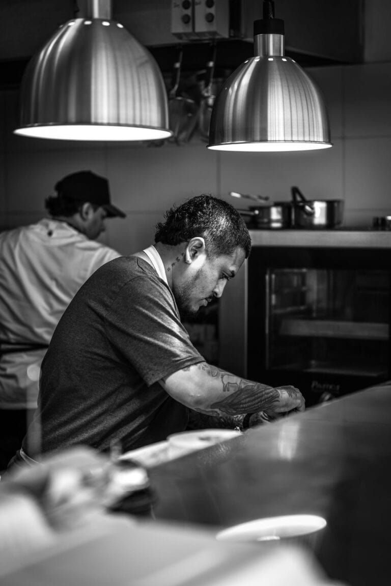 Barista making coffee behind the counter in a cozy cafe setting.