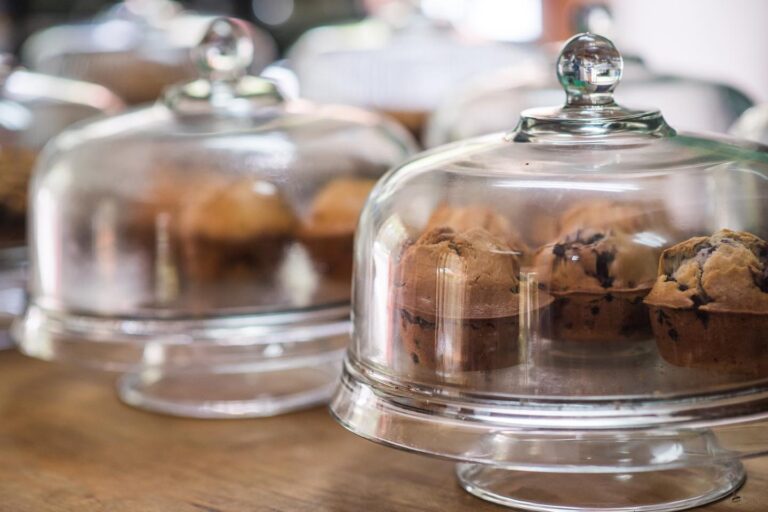 Glass domes display chocolate chip cookies on a wooden surface at a bakery or café in Roatan, Honduras.