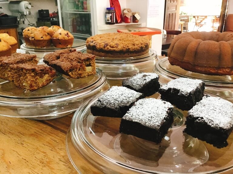 Assorted baked goods including brownies, cookies, and cake slices are displayed on glass plates inside a bakery or café in Roatan, Honduras.