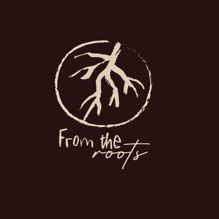 A logo featuring a tree root system enclosed in a circle with the text "From the roots" written below, representing a business on Roatan, Honduras.