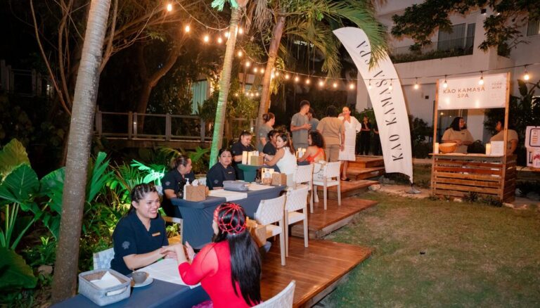 Outdoor evening scene at a Roatan spa with dining tables, string lights, and lush tropical plants, where guests are being served in a relaxed garden setting in Honduras.