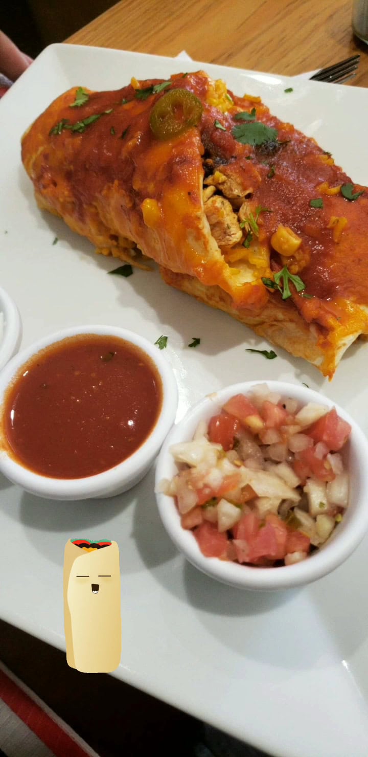 A plate with a Mexican-style tamale topped with tomato sauce, garnished with cilantro and jalapeño slices, accompanied by small bowls of salsa and pico de gallo on a wooden table in Roatan, Honduras.