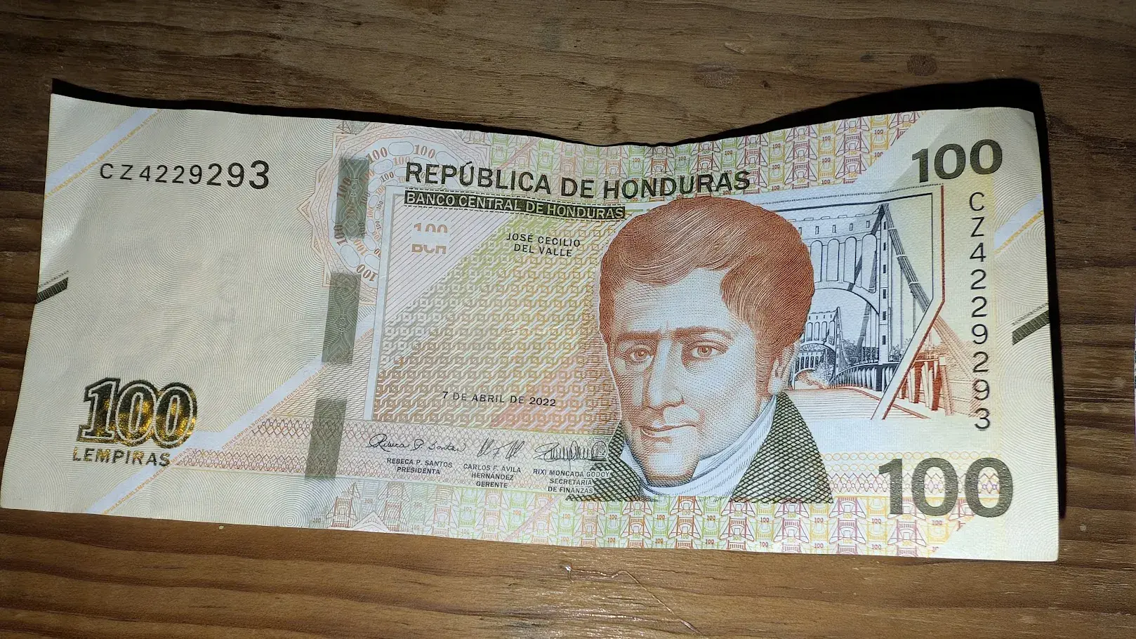 Honduran 100 lempira banknote featuring José Cecilio del Valle on a wooden table