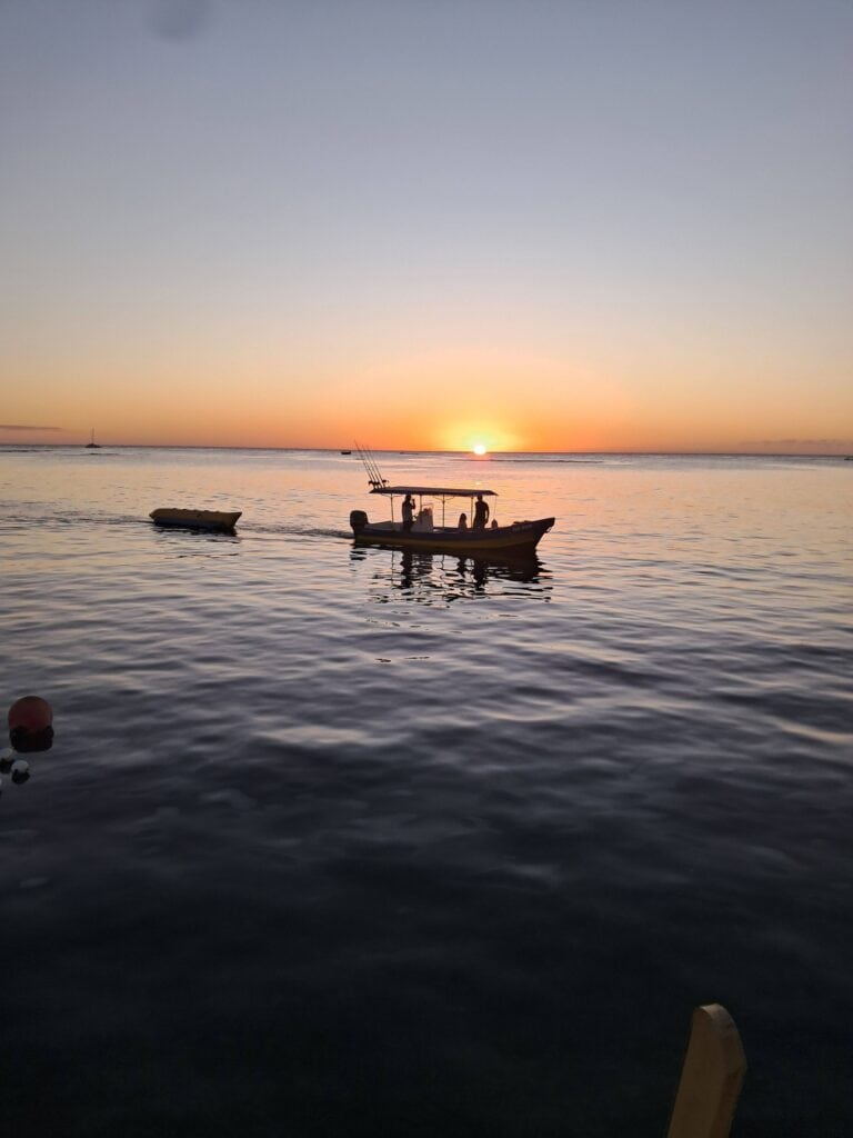 Sunset over calm waters with boats near Ipanema Beach Bar and Grill, Roatan, Honduras.