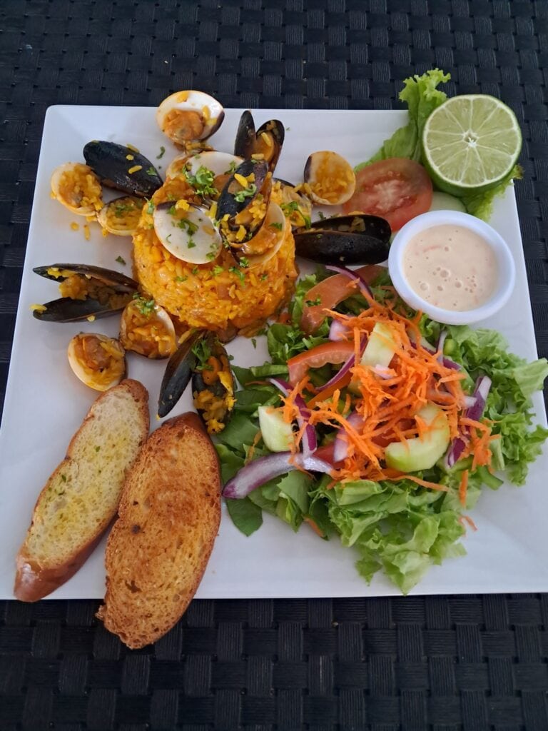 Seafood platter featuring mussels, shrimp, and fish served with fresh salad and toasted garlic bread.