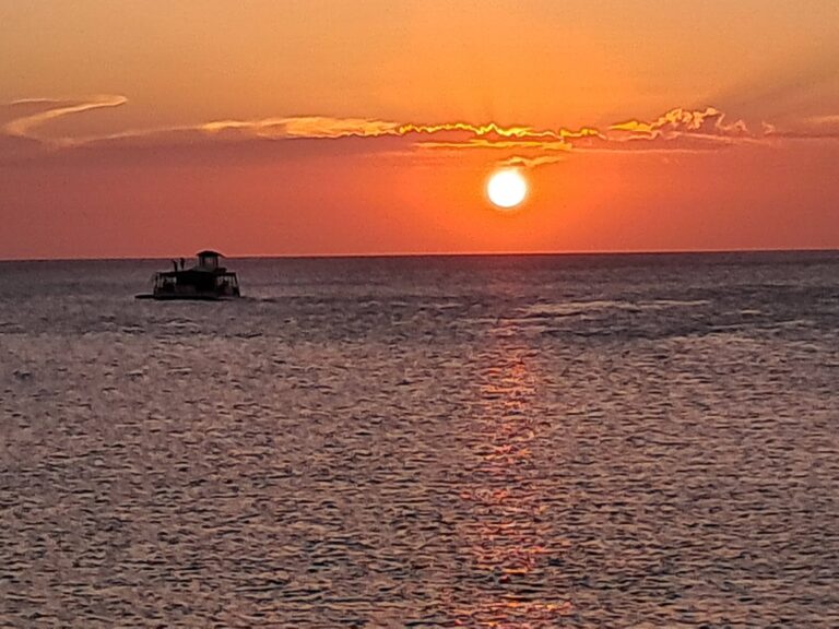Sunset view at Ipanema Beach Bar and Grill, Roatan, with calm waters and vibrant sky.