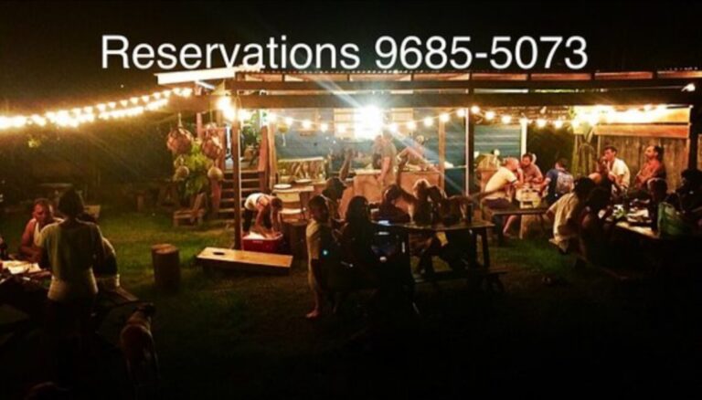 A lively outdoor dining area in Roatan, Honduras, illuminated by string lights with people sitting at tables and enjoying meals under a covered patio, with the reservation phone number displayed prominently at the top.