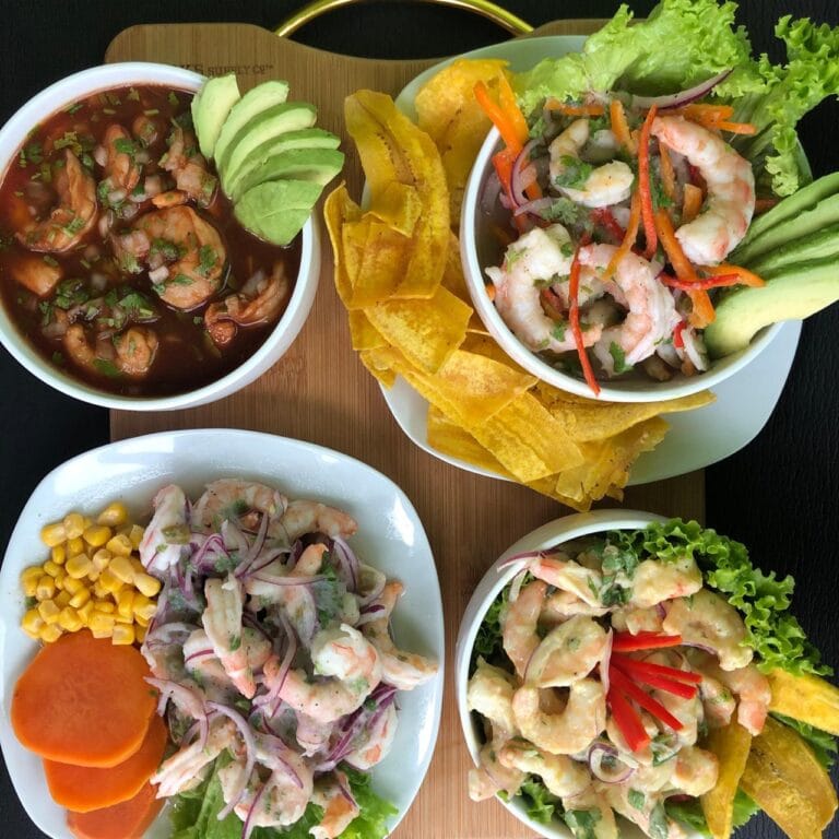 A variety of colorful seafood dishes, including shrimp salads, tortilla chips, and vegetable sides, are displayed on plates and bowls at a restaurant in Roatan, Honduras.