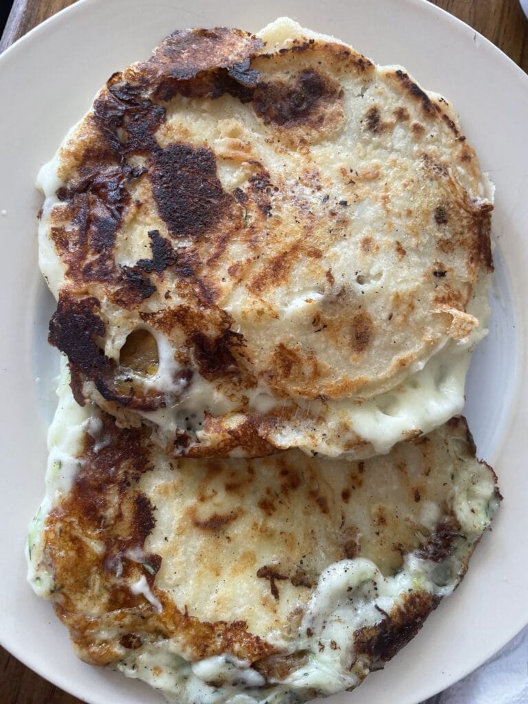 A plate of fried eggs with crispy edges and melted cheese, served on a white dish, is shown in this image from a business listing on RoatanYP.com in Roatan, Honduras.