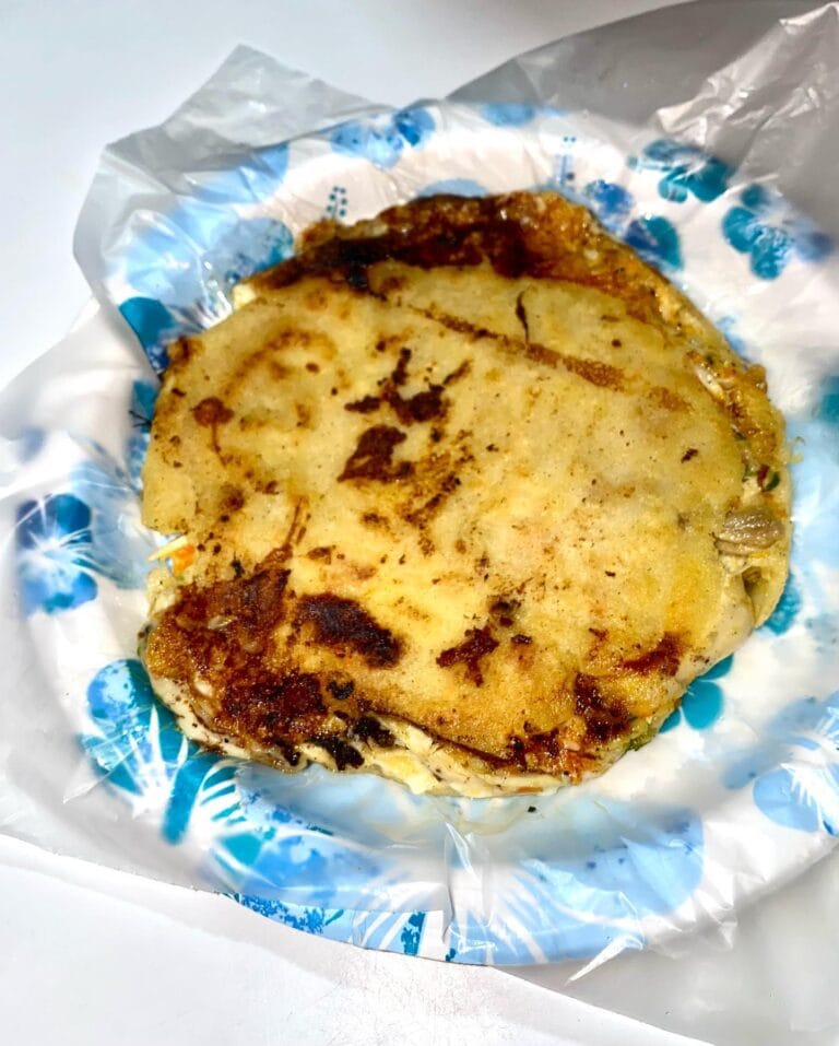 A grilled fish fillet served on parchment paper with blue floral patterns, placed on a white surface, representing local cuisine in Roatan, Honduras.