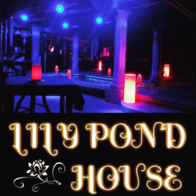 Night scene of Lily Pond House Restaurant illuminated with vibrant blue and red lights.