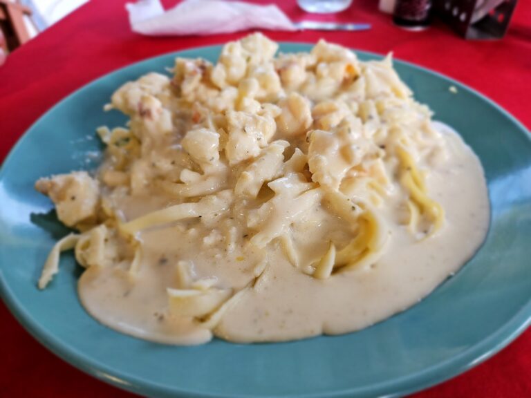 A plate of creamy potato salad with chopped ham and herbs sitting on a red tablecloth in a Roatan, Honduras restaurant.