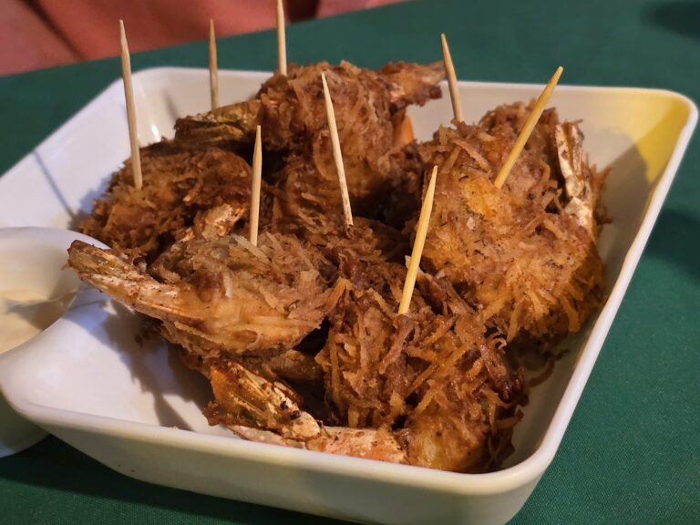 Crispy fried fish with shredded coconut on top served in a white dish at a restaurant in Roatan, Honduras.