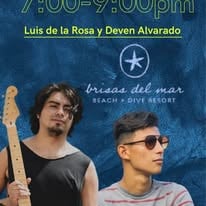 Two young men with sunglasses, one holding a guitar, stand against a blue backdrop advertising "Brisas del Mar Beach Dive Resort" in Roatan, Honduras.