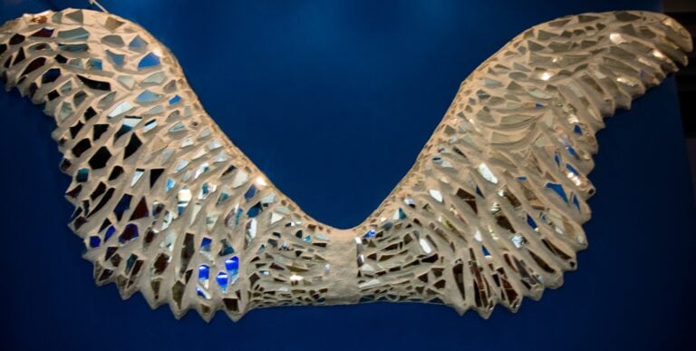A decorative white shell sculpture shaped like a butterfly hangs against a dark blue background in Roatan, Honduras.