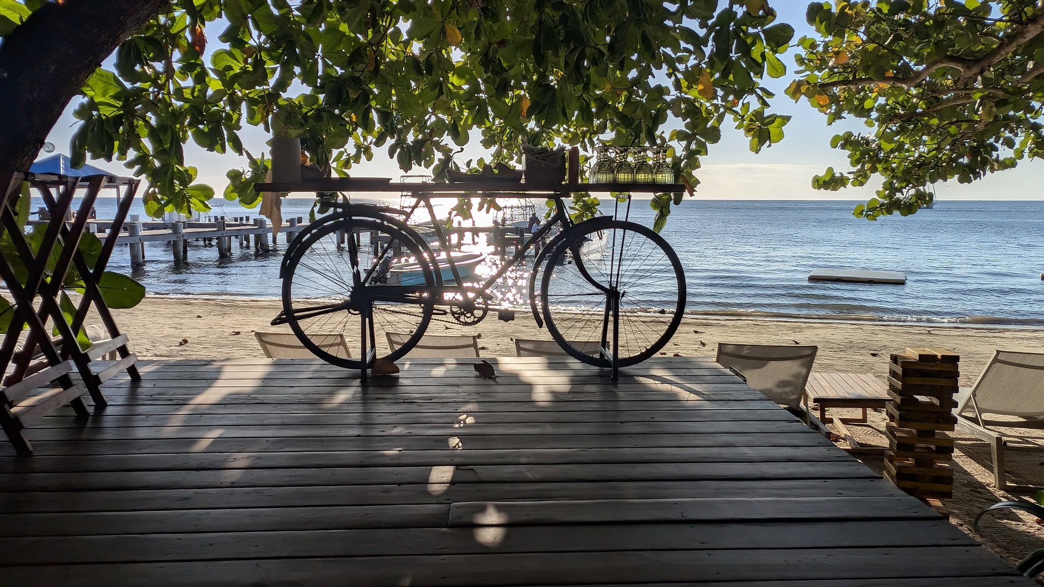 Bike on a wooden deck overlooking the beach at sunset in Roatan, Honduras.