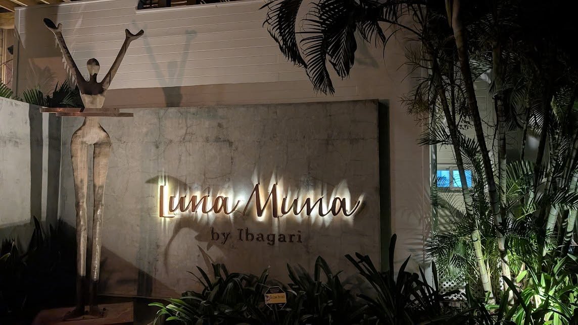 Elegant Luna Muna sign illuminated at night in a tropical setting.